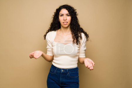 Photo for Frustrated hispanic woman shrugging her shoulders looking annoyed and with a lot of doubts - Royalty Free Image