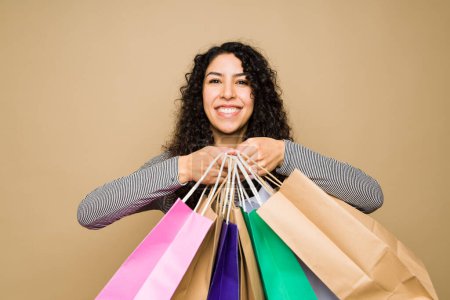 Téléchargez les photos : Portrait of an excited mexican woman showing a lot of shopping bags and looking very happy - en image libre de droit