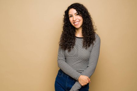 Foto de Attractive latin young woman wearing casual clothes and looking very happy and cheerful in front of a studio background - Imagen libre de derechos