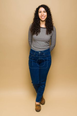 Téléchargez les photos : Full length of a gorgeous young woman with curly hair looking happy wearing casual clothes - en image libre de droit
