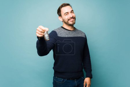Téléchargez les photos : Attractive happy man holding the car keys and looking cheerful after buying a new car - en image libre de droit