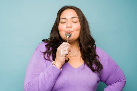 Foto de Relaxed attractive hispanic woman closing her eyes while eating delicious dessert with a spoon - Imagen libre de derechos