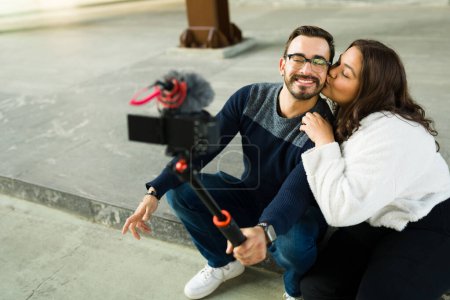Téléchargez les photos : Loving influencer couple kissing while filming a video blog and making content to post on their social media - en image libre de droit