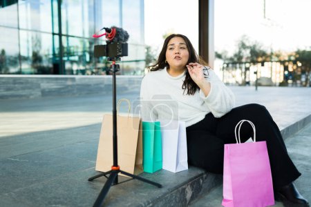 Photo pour Attractive latin woman influencer filming a video blog going shopping and making a product review - image libre de droit