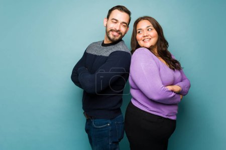 Photo for Handsome caucasian man flirting with a fat woman and looking at each other with their arms crossed - Royalty Free Image