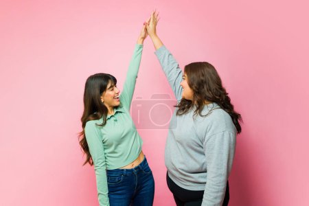 Photo for Happy women best friends smiling while doing a high five while dancing and having fun together - Royalty Free Image