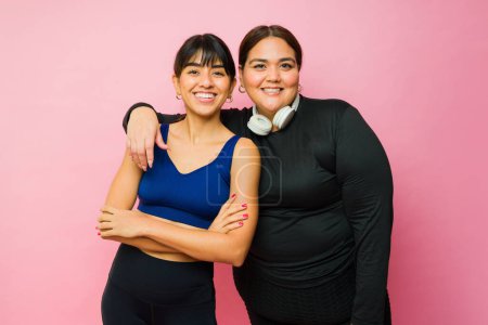 Foto de Hispanic attractive women friends wearing activewear smiling and hugging while ready to exercise - Imagen libre de derechos