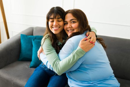 Photo for Loving attractive women best friends embracing while relaxing together on the sofa at home - Royalty Free Image