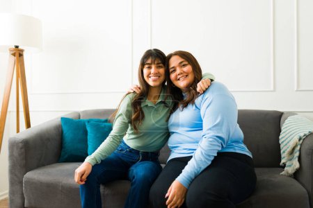 Photo for Beautiful happy best friends hugging and smiling while sitting together at home while hanging out - Royalty Free Image
