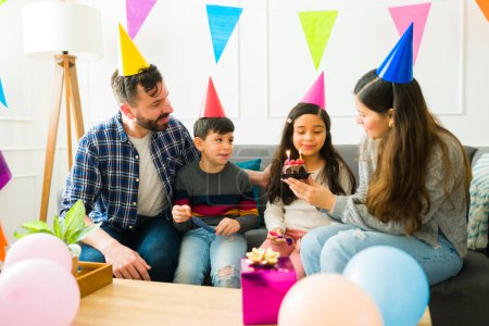 Foto de Happy mom and dad celebrating their daughter's birthday with a beautiful party with cake at home - Imagen libre de derechos