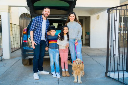 Foto de Full length of a beautiful family hugging and smiling while preparing the car trunk to take a road trip - Imagen libre de derechos