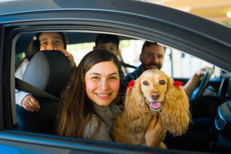 Foto de Attractive latin mom with her family and kids in the car traveling with a beautiful golden cocker spaniel dog - Imagen libre de derechos
