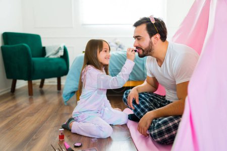 Téléchargez les photos : Caucasian dad putting on lipstick with his excited little girl daughter while playing putting on makeup - en image libre de droit