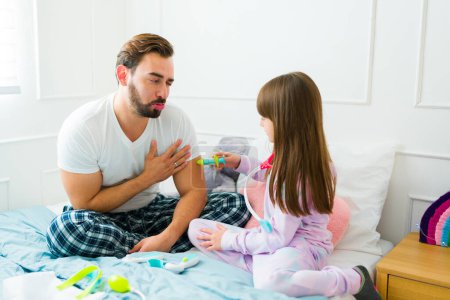 Photo for Loving dad and little girl using toy games and playing doctor together while in pajamas in the bedroom - Royalty Free Image