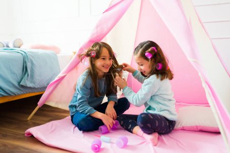 Foto de Little girls having a playdate smiling and playing doing different hairstyles having fun together on their play date - Imagen libre de derechos