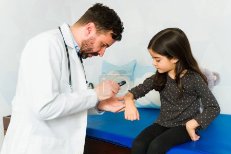 Foto de Médico profesional usando una lupa para ver la piel de una niña que tiene una reacción alérgica - Imagen libre de derechos
