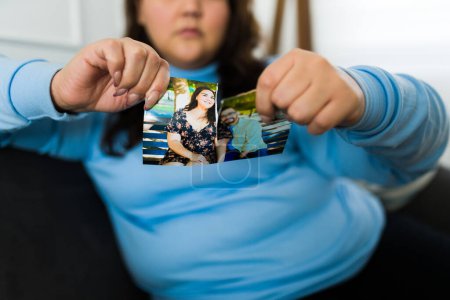 Téléchargez les photos : Femme hispanique brisant une photo avec son partenaire se sentant triste et bouleversé après une rupture déchirante - en image libre de droit