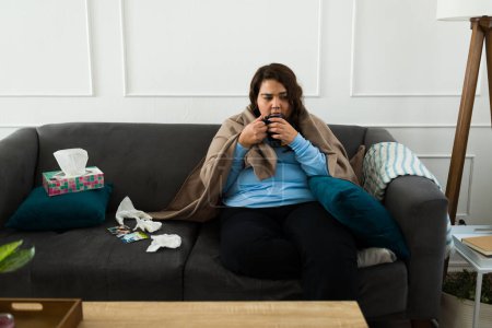Téléchargez les photos : Gros jeune femme se sentant triste et déprimé boire du thé chaud après avoir pleuré à la maison à cause de sa rupture - en image libre de droit