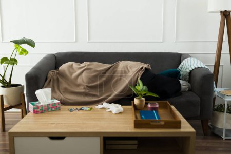 Foto de Depressed sad young woman lying on the sofa hiding under the covers while crying and missing her ex-boyfriend after a break-up - Imagen libre de derechos