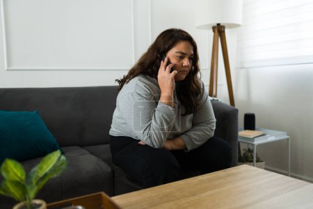 Photo for Upset sad young woman looking depressed while talking on the phone or calling someone asking for help because of her mental health problems - Royalty Free Image