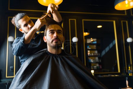 Photo for Male customer coming to the salon to cut his hair and a trendy hairstyle with a professional male hairstylist - Royalty Free Image