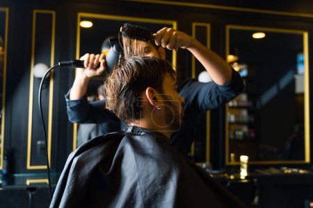 Photo for Caucasian man seen from behind while getting a new hairstyle after cutting his hair at the professional salon - Royalty Free Image
