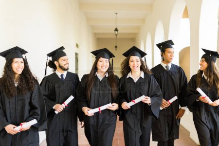 Téléchargez les photos : Heureux groupe d'amis riant et marchant après avoir reçu leur diplôme universitaire lors de leur cérémonie collégiale - en image libre de droit