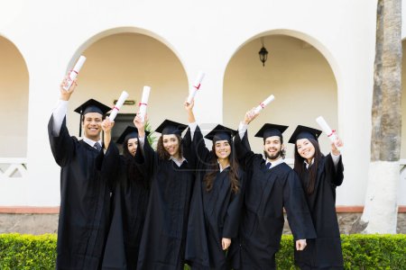 Photo for Attractive young women and men receiving their university diploma at graduation and celebrating - Royalty Free Image