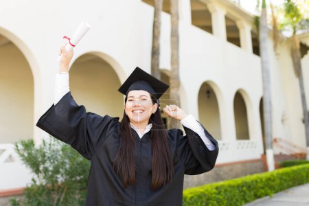 Téléchargez les photos : Très excitée de faire un contact visuel montrant son diplôme universitaire et de célébrer sa remise des diplômes au campus - en image libre de droit