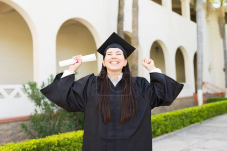 Téléchargez les photos : Femme super excitée diplômée criant de bonheur célébrant la réception de son diplôme lors de sa cérémonie de remise des diplômes - en image libre de droit