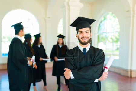 Téléchargez les photos : Attrayant diplômé mexicain sur un campus universitaire portant une robe de remise des diplômes après avoir reçu son diplôme universitaire - en image libre de droit