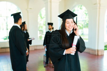 Téléchargez les photos : Belle diplômée parlant au téléphone avec sa famille en disant félicitations à cause de son diplôme universitaire - en image libre de droit