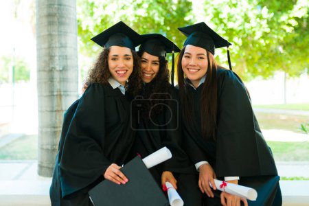 Foto de Portrait of smiling women college graduates with their university diplomas looking happy after their graduation ceremony - Imagen libre de derechos