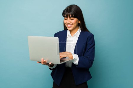 Téléchargez les photos : Joyeux professionnel jeune femme dactylographier sur l'ordinateur portable et de travailler sur ses affaires en ligne - en image libre de droit