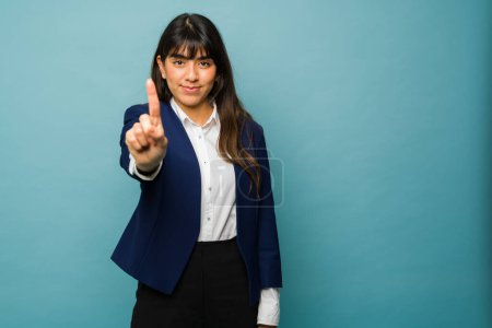 Foto de Smart confident young woman showing her index finger because her professional business is the number one - Imagen libre de derechos