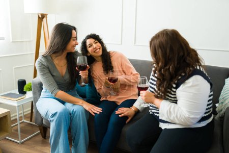 Photo for Happy best friends having the best fun time laughing while drinking wine together relaxing in the living room home - Royalty Free Image