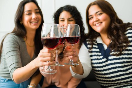 Photo for Happy beautiful young women having a fun time together as best friends while drinking wine and hanging out - Royalty Free Image