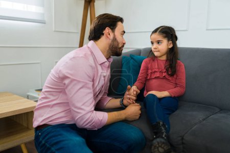Photo for Caring caucasian father explaining to her little daughter about divorce and child custody while talking sitting on the sofa - Royalty Free Image