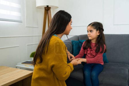 Besorgte liebevolle Mutter spricht auf dem Sofa mit ihrer kleinen Tochter über Scheidung und Sorgerecht