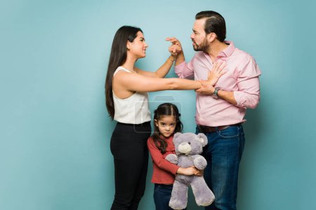 Photo for Furious angry couple yelling and fighting because of child custody problems of their sad adorable little girl - Royalty Free Image