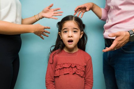 Photo for Surprised scared little child looking at the camera while listening to her parents fighting having marriage problems - Royalty Free Image