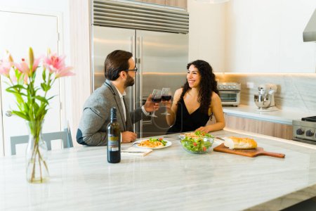 Photo for Excited woman and man making a toast while on a dinner elegant date at home and drinking wine - Royalty Free Image