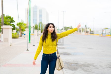 Téléchargez les photos : Jeune femme dans la vingtaine en attente d'un taxi ou d'une voiture de transport de service dans la ville - en image libre de droit