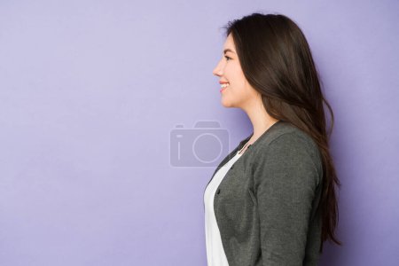Téléchargez les photos : Profil d'une belle femme asiatique dans la trentaine souriante regardant l'espace de copie sur un fond violet - en image libre de droit