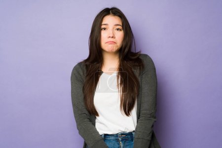 Foto de Triste mujer asiática en sus 30 años sintiéndose deprimida y molesta mientras mira a la cámara delante de un fondo púrpura - Imagen libre de derechos