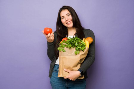 Foto de Retrato de una mujer caucásica sana sonriendo sintiéndose feliz comprando verduras y llevando una compra de comestibles - Imagen libre de derechos