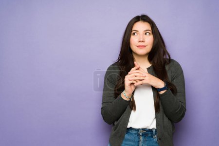 Photo for Thoughtful asian woman in her 30s looking and up and thinking about a new smart idea or using her imagination - Royalty Free Image