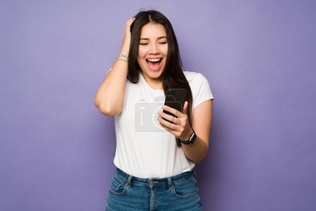 Photo for Excited beautiful woman receiving a surprise text message on the smartphone or looking at social media - Royalty Free Image