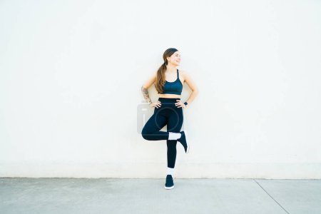 Photo for Cheerful active young woman smiling and enjoying her run or cardio workout outdoors while practicing sports - Royalty Free Image