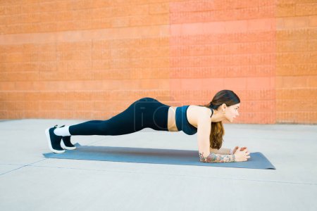 Téléchargez les photos : Profil d'une jeune femme athlétique ayant un style de vie physique faisant des exercices de planche à l'extérieur - en image libre de droit